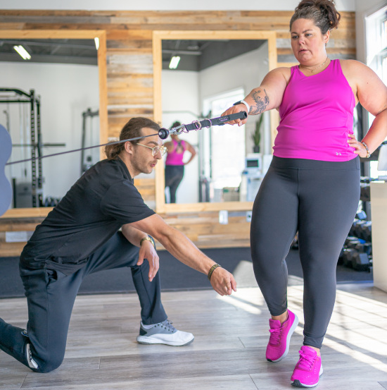 Personal fitness instructor teaching client correct body movement in gym