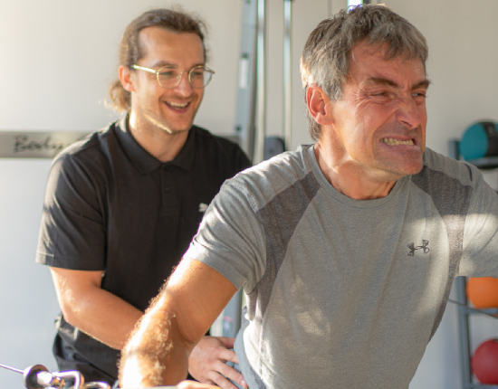 Gym instructor with patient performing standing incline machine cable flyes